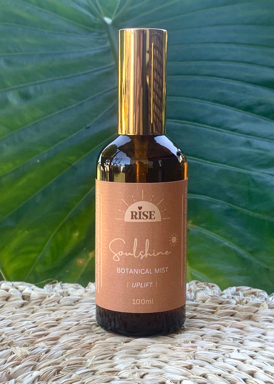 amber glass bottle of aromatherapy soulshine mist on woven mat with largedark green leaf in the background